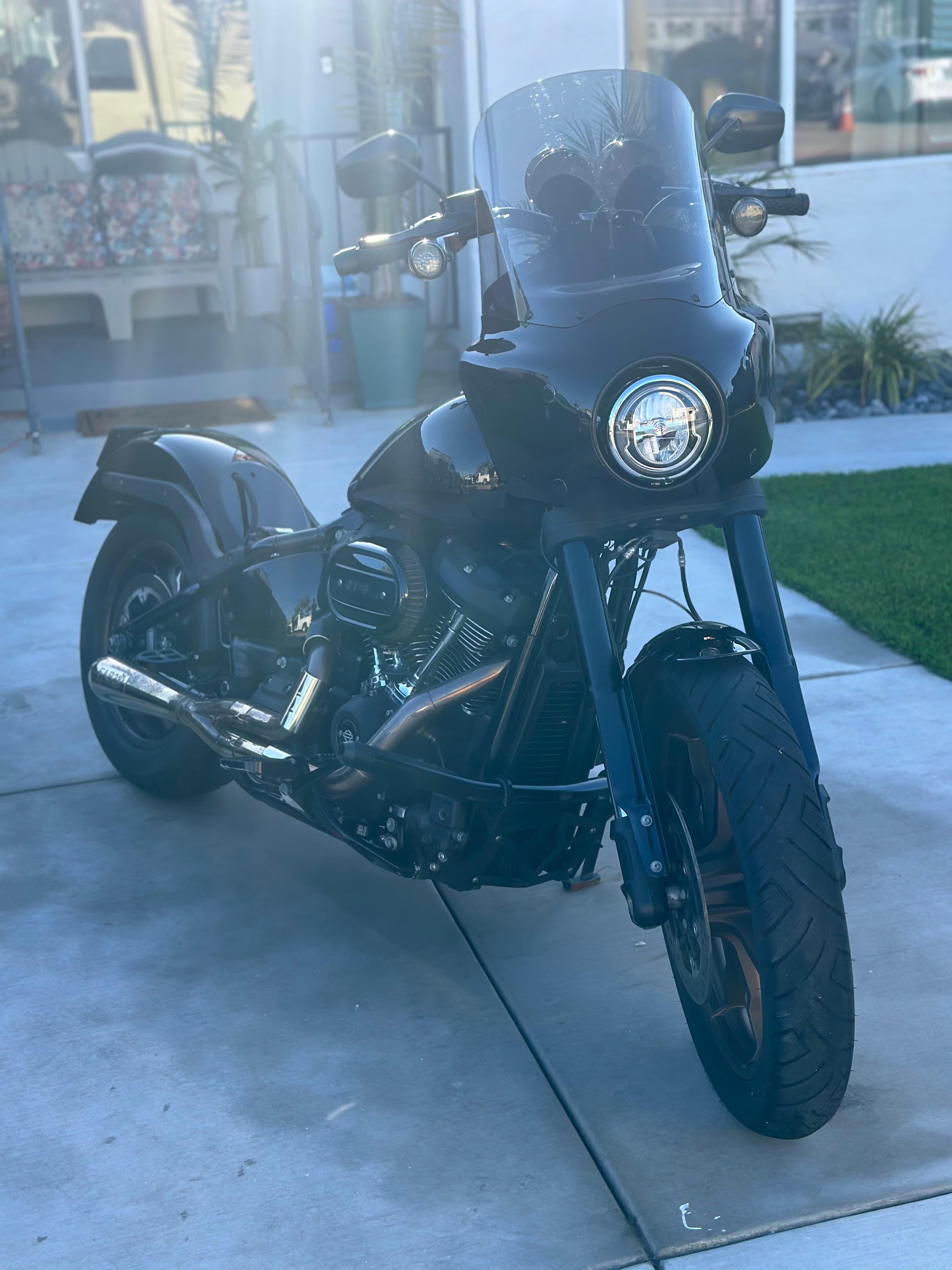 Sleek black cruiser motorcycle with a large front fairing parked on a sunny concrete driveway.